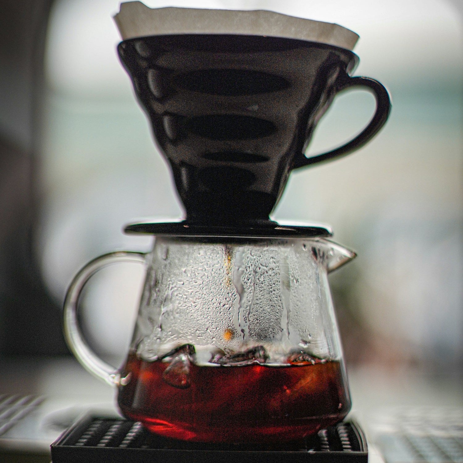 Coffee brewing process with a glass carafe and filter on a blurred background