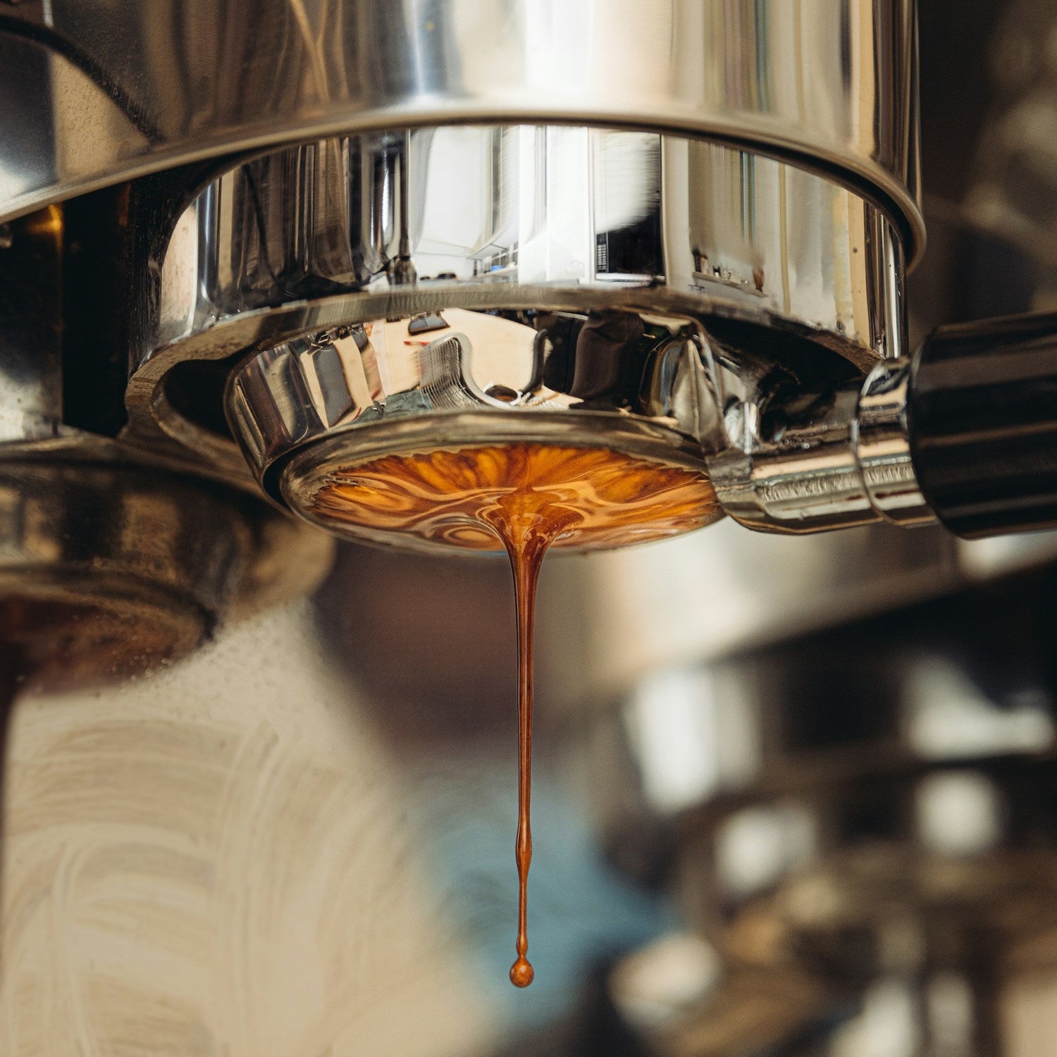 Close-up of coffee being brewed from a espresso machine with a focus on the stream of coffee.